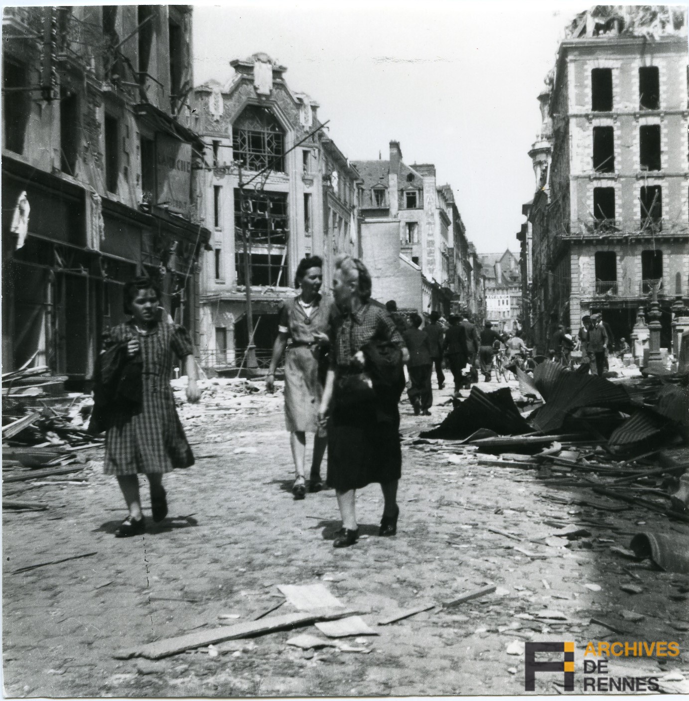 Photo : Lorsque les Rennais sortent des abris ils ne peuvent que constater les dégâts. Ces Rennaises s’engageant dans la rue de Nemours ne semblent plus reconnaître leur ville. 